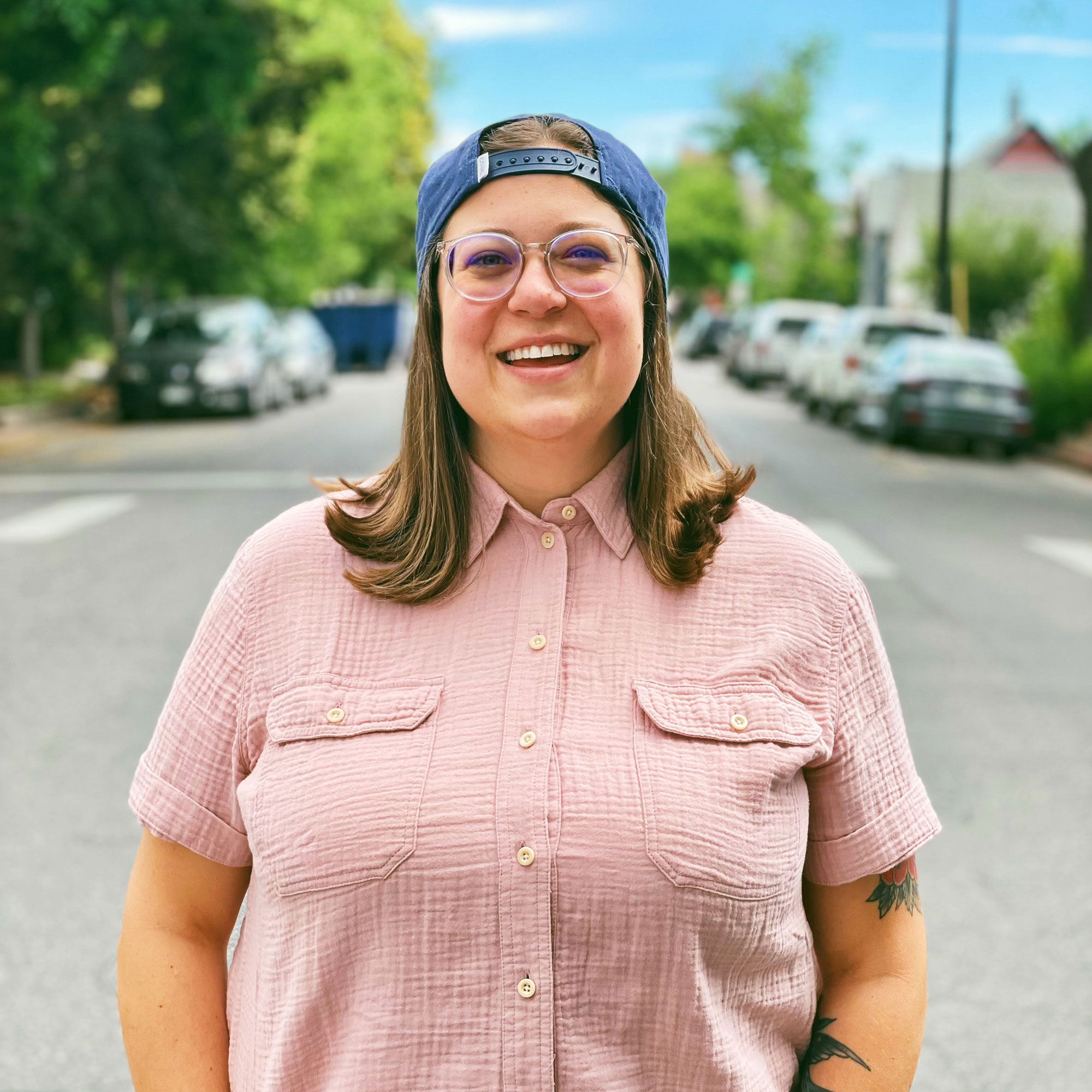 Kate Farrar smiling in a street lined with trees and cars